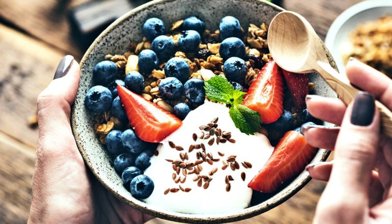 A woman eats a yogurt bowl filled with fruit