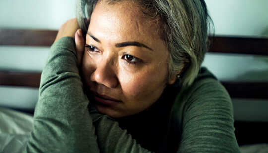 A woman sitting in bed leans on her arms