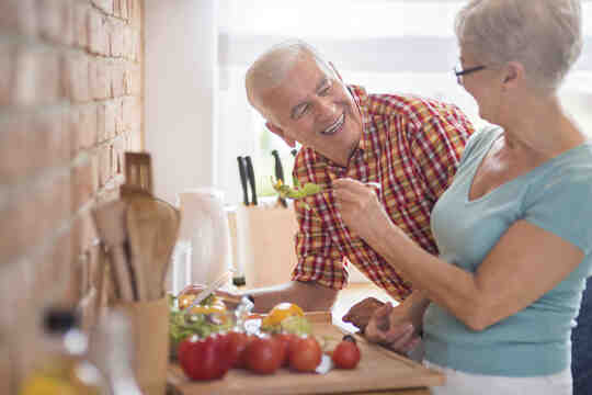 An older couple preparing vegetables in the kitchen.