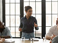 A young leader sitting at a desk, confidently reviewing documents and charts, symbolizing the process of making thoughtful, strategic decisions in a high-pressure work environment.