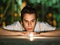 a young man laying down staring into a candle flame