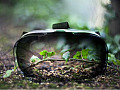 A VR headset with sprouting green leaves reflected on its surface represents the debate on whether virtual nature can provide the same wellness benefits as real nature.