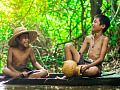 two boys sitting by the water and laughing joyfully