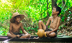 two boys sitting by the water and laughing joyfully