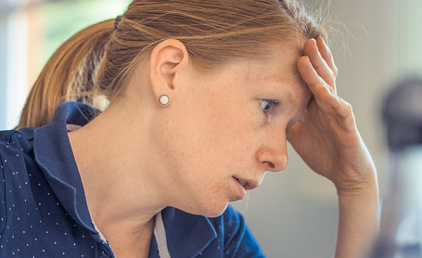 a woman in concentration resting her forehead on her hand