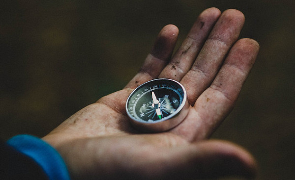 a man in a suit holding a compass in his open hand