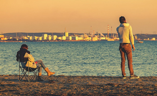 two people igoring each other... one sitting the other standing some distance away