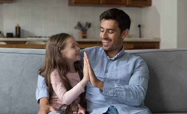 A warm, natural scene of a parent sitting down to the eye level of a young child