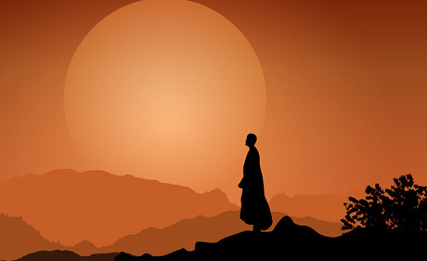 a monk standing peaceful in front of the setting sun