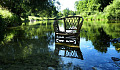 a wicker chair in the calm waters of a river near the riverbank