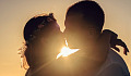 two people kissing with the light shining brightly behind them