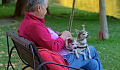 a white-haired woman sitting outside with two small dogs on her lap