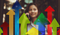 woman standing behind a row of colorful graphical arrows pointing up